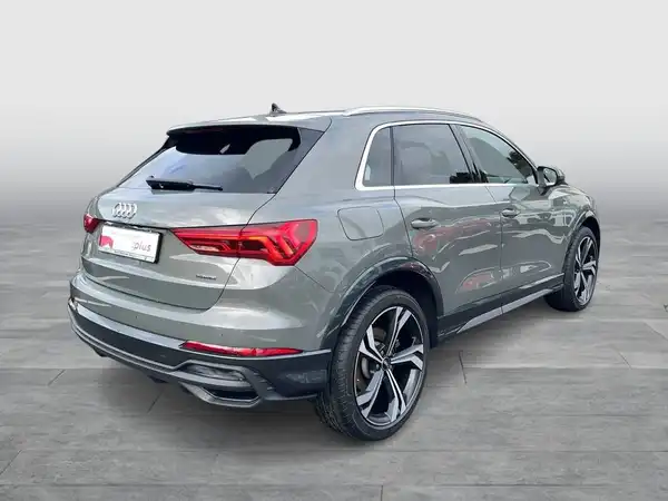 Das Bild zeigt einen grauen AUDI Q3 von hinten aufgenommen. Es handelt sich um ein Fahrzeugbild.