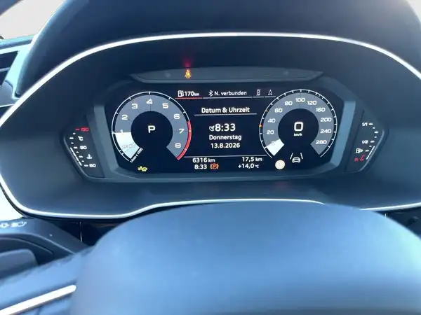 Das Bild zeigt das Armaturenbrett und das digitale Cockpit eines AUDI Q3. Die Anzeige zeigt Informationen wie Datum, Uhrzeit und Fahrdaten.
