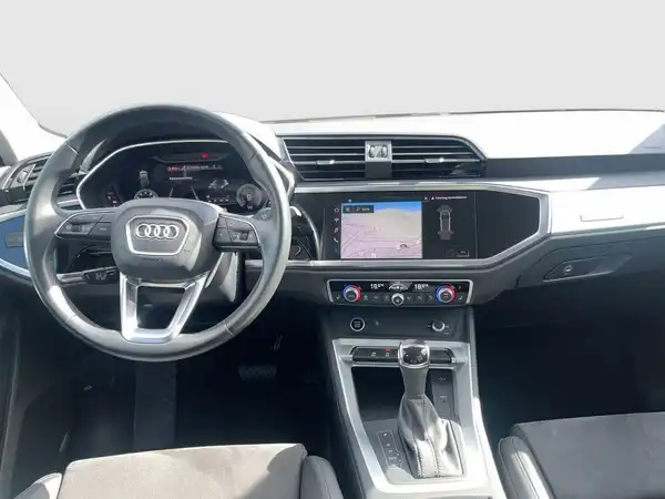Das Bild zeigt das Inneninterieur eines AUDI Q3 in schwarz. Es enthält ein Navigationsdisplay sowie markante Texteinblendungen.