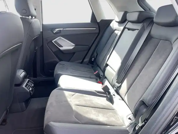 Das Bild zeigt den Innenraum des Audi Q3, speziell die Rückbank. Die Sitze sind aus schwarzem Material.