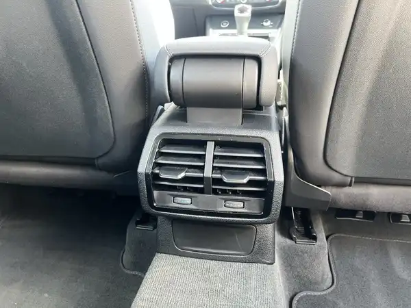 Das Bild zeigt den Innenraum eines Fahrzeugs, konkret die Klimaanlage zwischen den Sitzen, der Bezug ist schwarz.