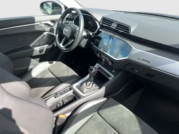 Das Bild zeigt den Innenraum eines AUDI Q3. Der Innenraum ist hauptsächlich schwarz.