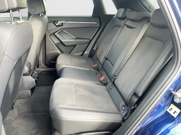 Das Bild zeigt den Innenraum eines AUDI Q3 aus der Sicht der Rücksitze, in der Farbe blau mit schwarzem Interieur.