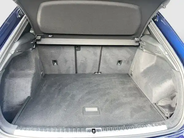 Ein Bild des Kofferraums eines blauen Audi Q3, aufgenommen von hinten, mit grauem Innenraum.