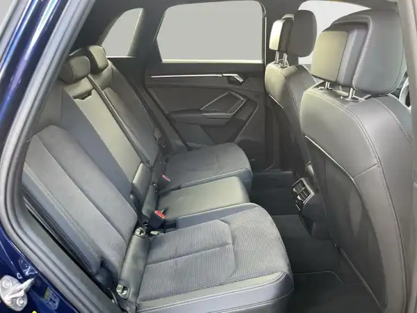 Das Bild zeigt den Innenraum des Audi Q3, spezifisch die Rückbank. Die Rücksitze sind schwarz und haben eine moderne Polsterung.