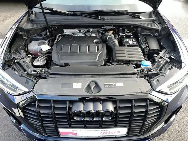 Das Bild zeigt den Motorraum eines AUDI Q3, aufgenommen von oben. Es enthält das Händlerlogo und einige markante Texteinblendungen.