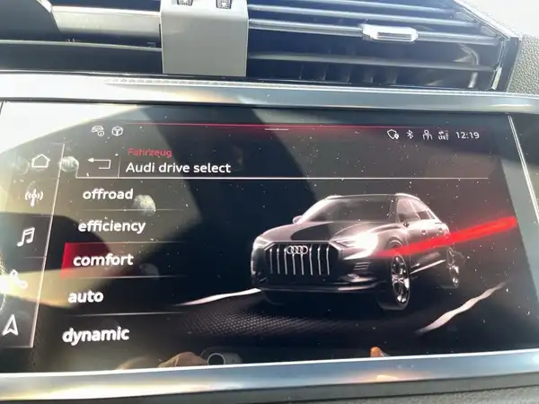 Die Innenaufnahme zeigt das Infotainment-System des AUDI Q3 mit einem digitalen Display, das die Fahrzeugsteuerung und -einstellungen anzeigt.