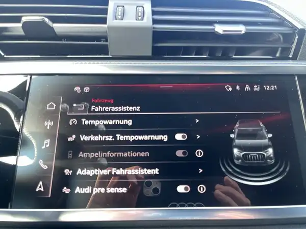 Das Bild zeigt das Innenleben eines Audi Q3 mit einem Infotainment-Display, auf dem verschiedene Fahrassistenzinformationen angezeigt werden.