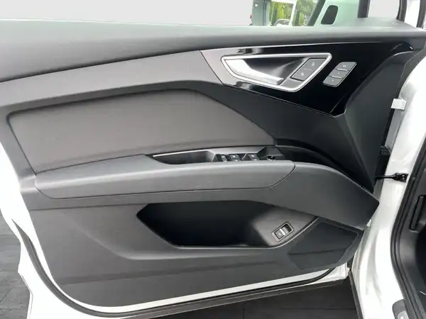 Das Bild zeigt die Innenansicht der Fahrertür eines AUDI Q4 E-TRON in weiß mit schwarzem und grauem Interieur.