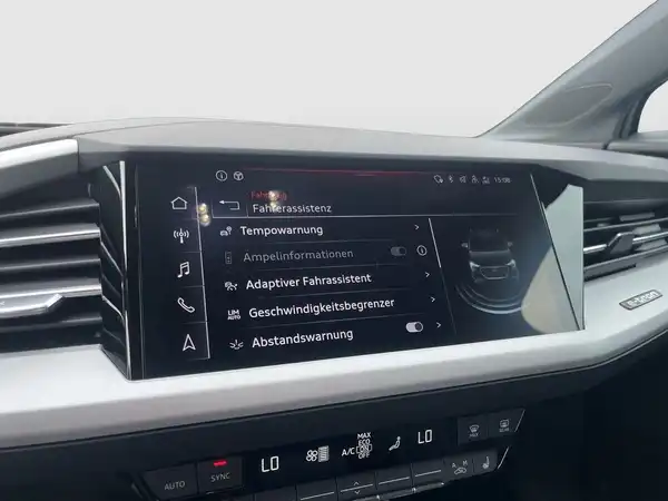 Innenaufnahme des AUDI Q4 E-TRON mit einem Bildschirm, der verschiedene Fahrassistenzsysteme und Einstellungen anzeigt.