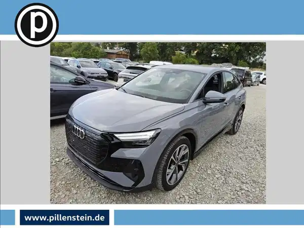 Das Bild zeigt einen grauen Audi Q4 E-Tron von der Seite. Es ist ein Fahrzeugbild, und das Händlerlogo ist vorhanden.