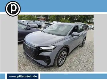 Das Bild zeigt einen grauen Audi Q4 E-Tron von der Seite. Es ist ein Fahrzeugbild, und das Händlerlogo ist vorhanden.