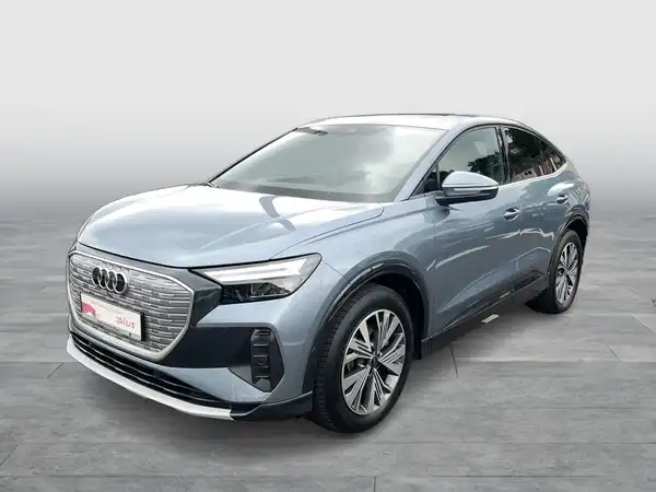 Das Bild zeigt einen AUDI Q4 SPORTBACK E-TRON von der Seite in blauer Farbe. Es enthält markante Texteinblendungen.