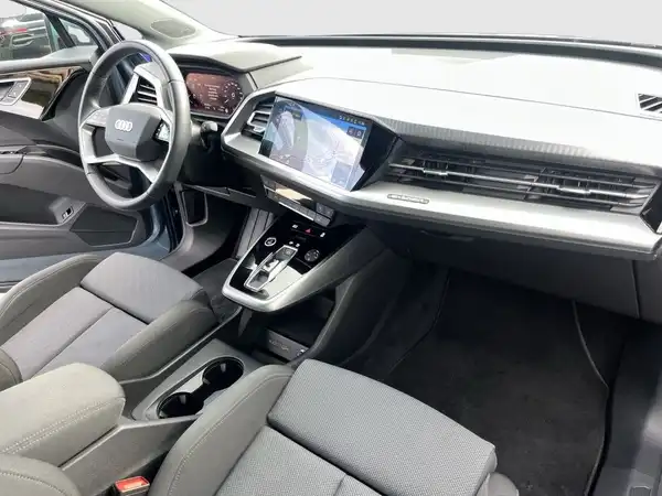 Innenaufnahme des AUDI Q4 SPORTBACK E-TRON mit schwarzem Interieur und grauen Akzenten.