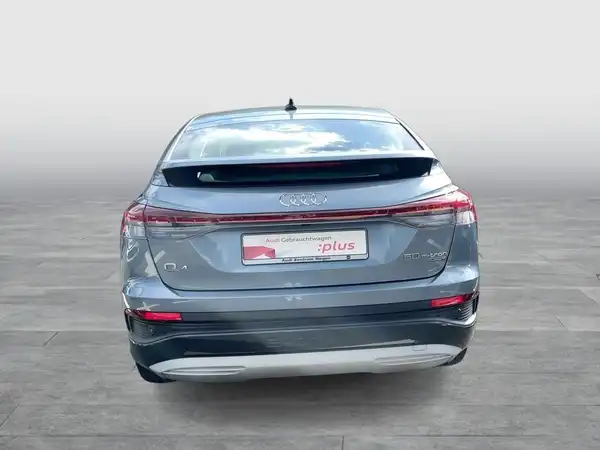 Das Bild zeigt die Rückansicht eines grauen AUDI Q4 SPORTBACK E-TRON. Es ist ein Fahrzeugbild mit Händlerlogo und markantem Text.