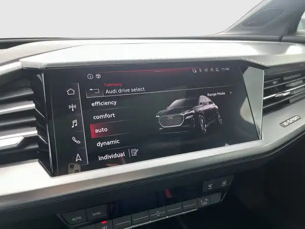 Das Bild zeigt das Innere eines AUDI Q4 SPORTBACK E-TRON mit einem Navigationssystem. Das Innenraumdesign ist modern und die Hauptfarbe des Interieurs ist Schwarz.