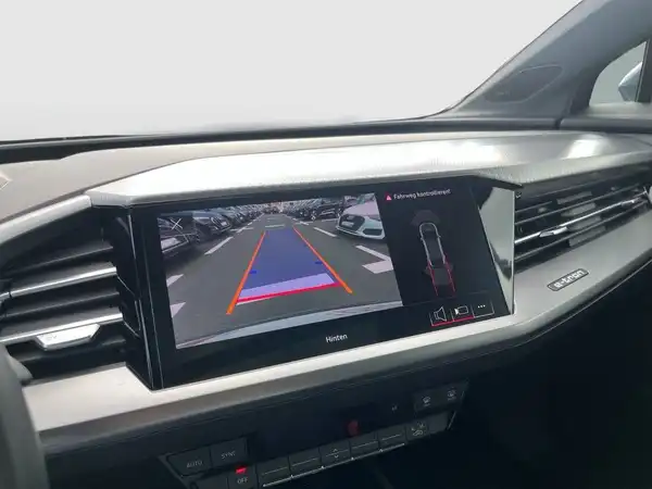 Das Bild zeigt den Innenraum eines AUDI Q4 SPORTBACK E-TRON mit einem Displayscreen, der die Rückfahrkamera anzeigt.