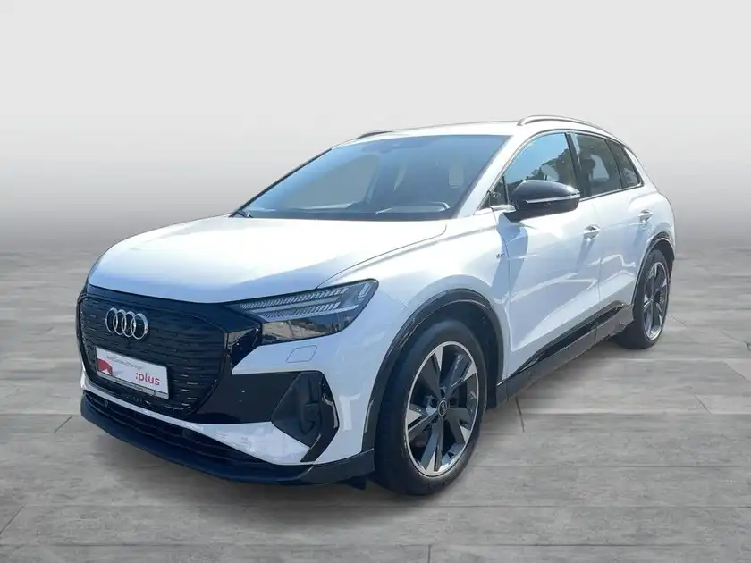 Das Bild zeigt einen weißen AUDI Q4 E-TRON aus der Seitenansicht. Ein Händlerlogo ist sichtbar und es gibt markante Texteinblendungen.