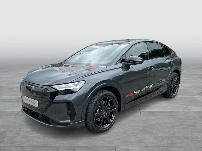 Das Bild zeigt einen schwarzen AUDI Q4 SPORTBACK E-TRON aus der Seitenansicht. Das Fahrzeug hat ein Händlerlogo und enthält markante Texteinblendungen.