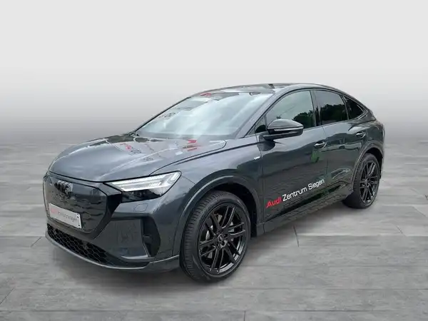 Das Bild zeigt einen schwarzen AUDI Q4 SPORTBACK E-TRON aus der Seitenansicht. Das Fahrzeug hat ein Händlerlogo und enthält markante Texteinblendungen.
