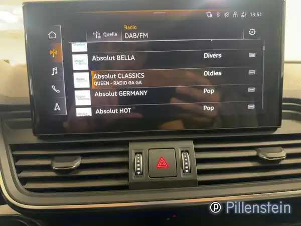 Das Bild zeigt das Innenleben eines Audi Q5 mit einem Infotainment-Bildschirm, der Radiosender anzeigt. Der Innenraum ist in Schwarz gehalten und enthält das Händlermarke Pillenstein.
