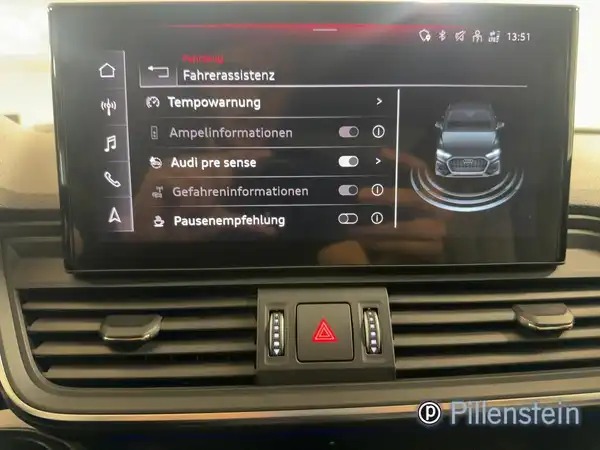 Das Bild zeigt das Innenraumdisplay eines AUDI Q5 mit einer Übersicht der Fahrassistenzsysteme. Das Interieur ist in schwarzer Farbe gehalten und das Foto enthält ein Händlerlogo.