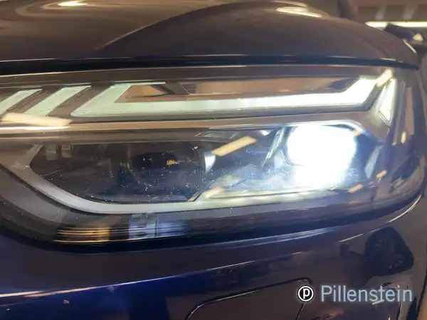 Das Bild zeigt den Frontscheinwerfer eines blauen AUDI Q5, aufgenommen von vorne.