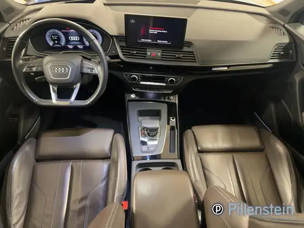 Das Bild zeigt den Innenraum eines Audi Q5 aus der Vogelperspektive. Die Sitze sind braun und es gibt ein Händlernlogo.