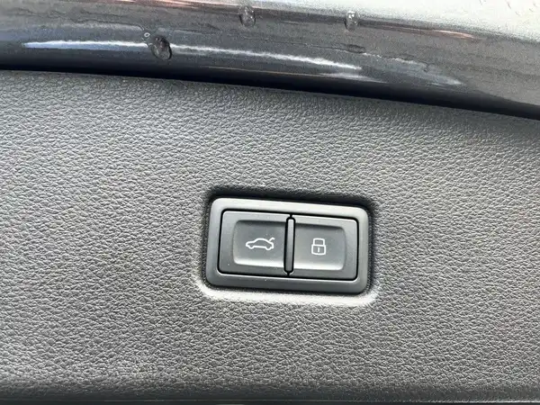 Das Bild zeigt das Interieur eines Audi Q5 mit zwei Tasten am Armaturenbrett. Die Tasten sind schwarz und gehören zu den Funktionen für das Auto.