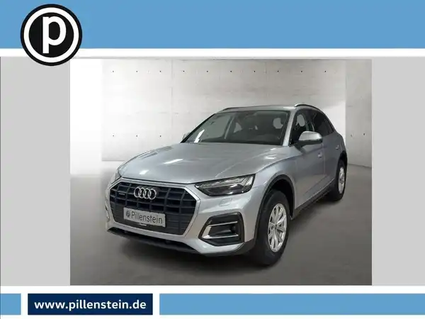 Das Bild zeigt einen silbernen Audi Q5 von vorne. Es handelt sich um ein Fahrzeugbild, das ein Händlersymbol in der oberen linken Ecke und eine Webadresse am unteren Rand enthält.