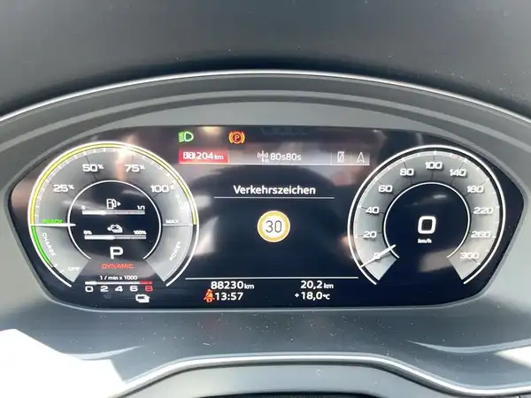 Das Bild zeigt das digitale Cockpit eines Audi Q5 von innen, mit Informationen wie Geschwindigkeit und Verkehrsschildern, auf einem schwarzen Armaturenbrett.