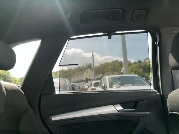 Innenaufnahme des Fahrzeugs, zeigt den Rücksitzbereich und das Fenster mit Aussicht nach draußen. Das Interieur ist schwarz.