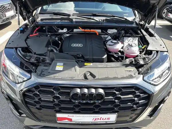 Das Bild zeigt den Motorraum eines AUDI Q5. Es handelt sich um eine Innenaufnahme des Fahrzeugs. Im Bild ist ein Händlerlogo zu sehen und es gibt markante Texteinblendungen.