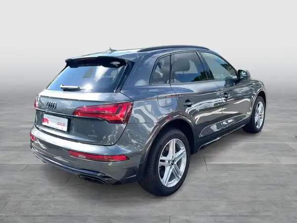 Das Bild zeigt einen grau lackierten AUDI Q5 von hinten, aus einem leichten seitlichen Blickwinkel. Es gibt hervorstechende Texteinblendungen auf dem Bild.