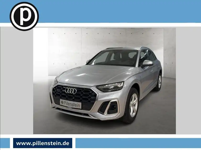 Das Bild zeigt einen silbernen Audi Q5 frontal aufgenommen. Im Hintergrund ist ein Händlertlogo sowie eine Website eingeblendet.