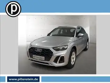 Das Bild zeigt einen silbernen Audi Q5 frontal aufgenommen. Im Hintergrund ist ein Händlertlogo sowie eine Website eingeblendet.