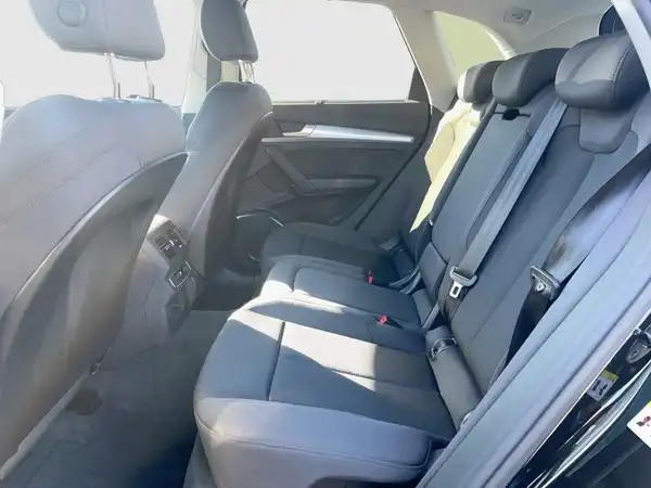 Das Bild zeigt den Innenraum eines AUDI Q5 von der Rückbank, in schwarzem Farbton mit grauem Stoff.