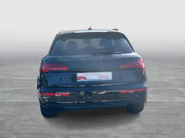 Das Bild zeigt den hinteren Teil eines schwarzen AUDI Q5. Das Fahrzeug ist von hinten aufgenommen und trägt ein Händlerlogo mit markanten Texteinblendungen.