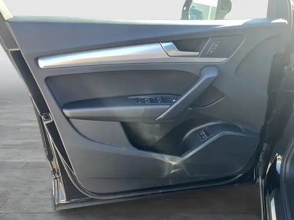 Das Bild zeigt die Innenaufnahme der Fahrertür eines AUDI Q5 in der Farbe Schwarz. Die Tür besteht aus schwarzem Kunststoff und Textil.