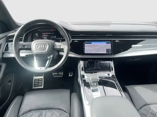 Das Bild zeigt das Inneninterieur eines Audi Q8, mit einem schwarzen Interieur und markanten Texteinblendungen auf dem Bildschirm.