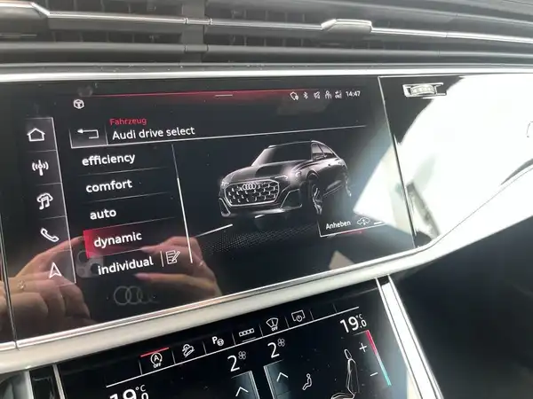 Das Bild zeigt das Innenleben eines Audi Q8, fokussiert auf das Infotainmentsystem. Die Innenfarbe des Fahrzeugs ist schwarz.