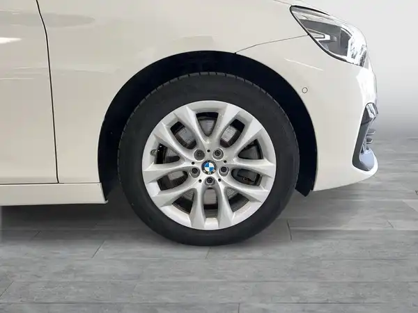 Das Bild zeigt die Seite eines weißen BMW 225, das Fahrzeug ist auf einem holzähnlichen Boden abgebildet.