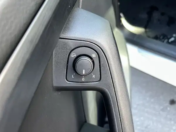 Das Bild zeigt eine Innenaufnahme des Fahrzeugs, speziell einen Schalter an der Fahrertür. Der Schalter ist schwarz und ermöglicht die Einstellung der elektrischen Seitenspiegel.