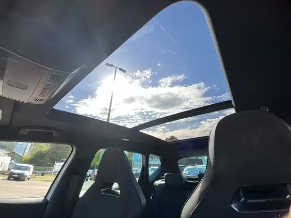 Innenaufnahme eines Fahrzeugs mit einem Panoramadach und schwarzen Sitzen.
