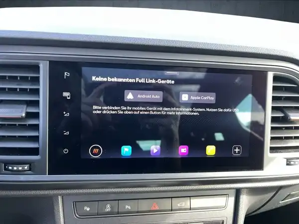 Das Bild zeigt den Innenraum eines Fahrzeuges mit einem Infotainment-Display. Das Display zeigt verschiedene Optionen wie Android Auto und Apple CarPlay an.