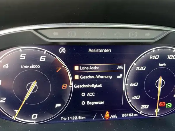 Eine Innenaufnahme des Fahrzeugs, die ein digitales Display mit verschiedenen Informationen zeigt, einschließlich Assistenzsysteme und Geschwindigkeitsanzeigen.