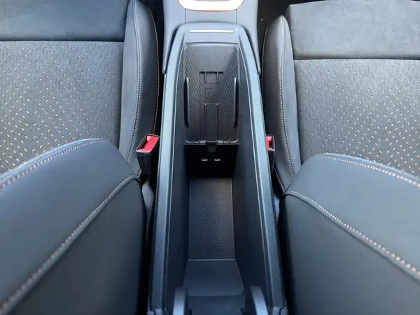 Das Bild zeigt den Innenraum eines Fahrzeugs, aufgenommen von oben, mit schwarzem Interieur und einem zentralen Ablagebereich zwischen den Sitzen.