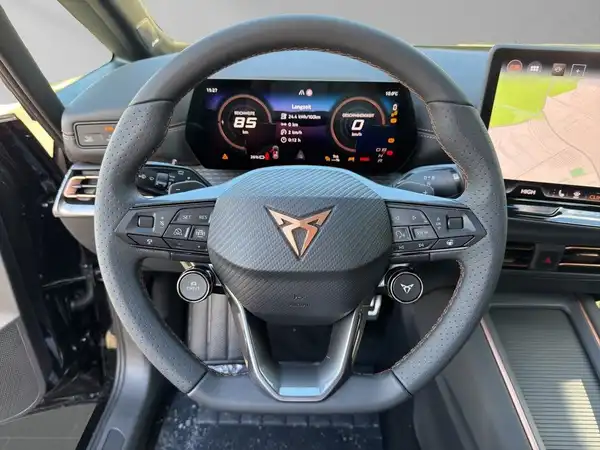 Das Bild zeigt das Innenraum eines CUPRA BORN mit einem modernen schwarzen Lenkrad und einem digitalen Cockpit.