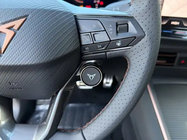 Das Bild zeigt das Lenkrad und Teile des Innenraums eines CUPRA BORN. Das Interieur ist in Schwarz mit roten Akzenten gehalten.