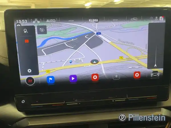 Das Bild zeigt den Innenraum eines Fahrzeugs mit einem Bildschirm, der eine Navigationskarte anzeigt. Im Hintergrund ist ein Händlerlogo sichtbar.